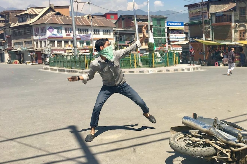 A young protestor hurls a rock