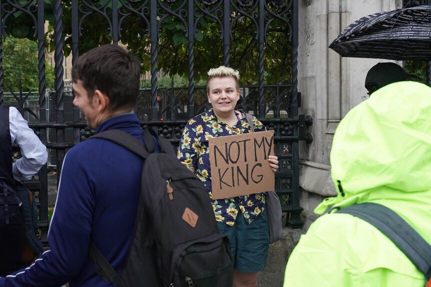 A young woman holds a Not My King sign 