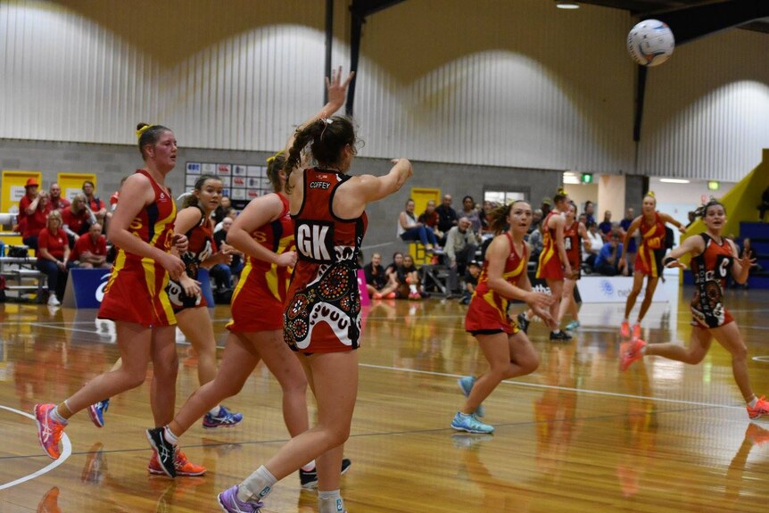 Gabby Coffey throws the ball while playing in an Indigenous netball dress