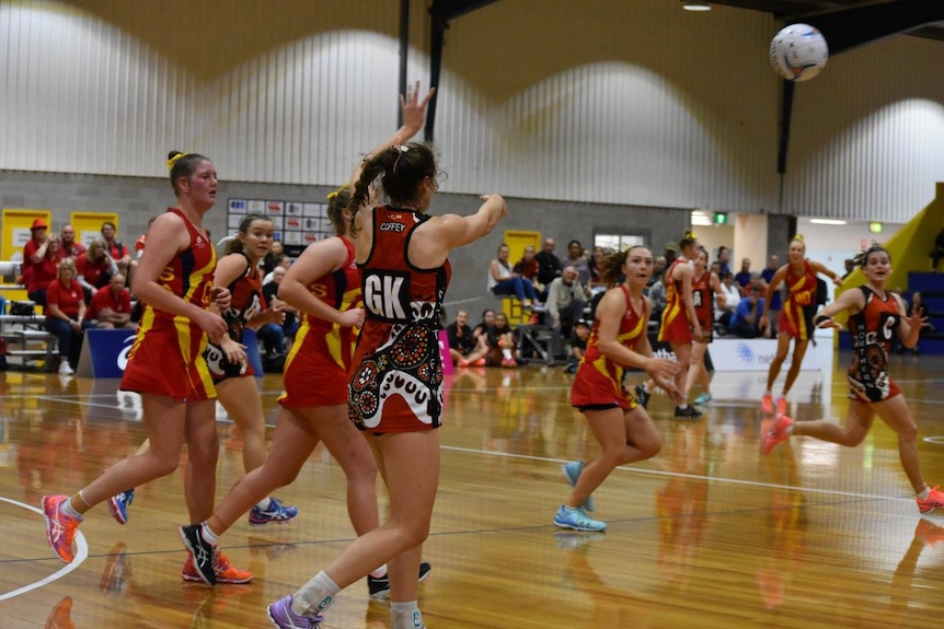 Gabby Coffey throws the ball while playing in an Indigenous netball dress