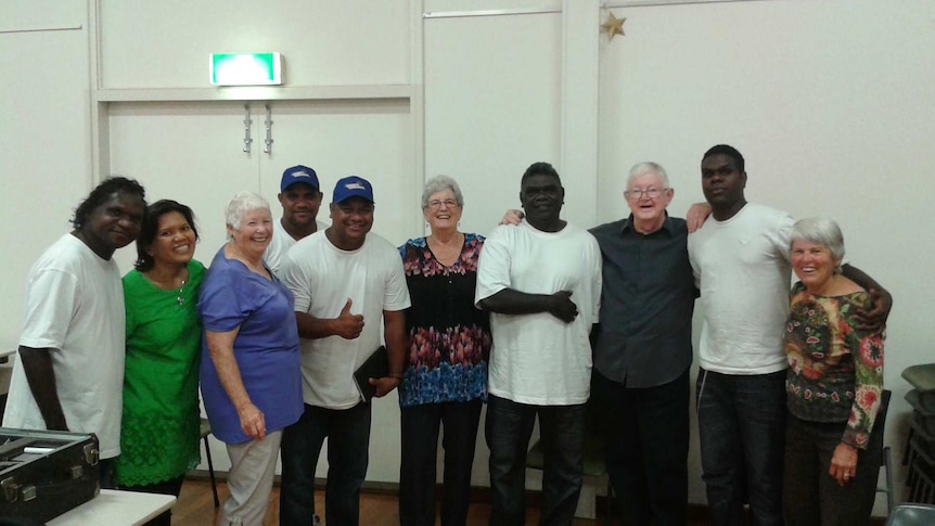 A group of mixed ages and races of people smile for the camera.