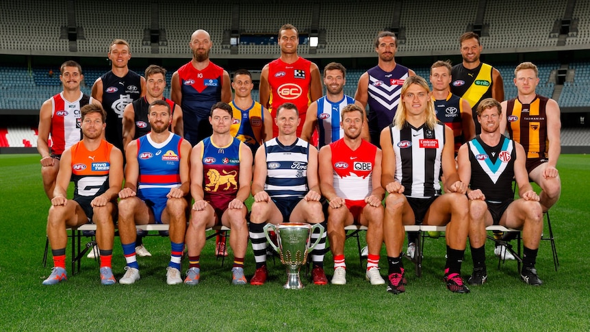 The eighteen AFL club captains sitting on a bench with one of them very big 