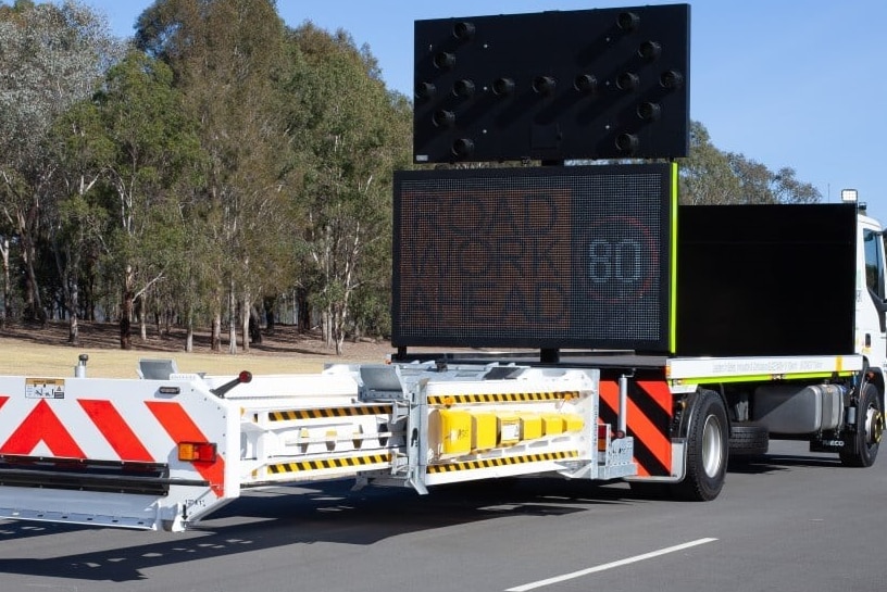 A modified truck with a road work ahead sign mounted on the trailer