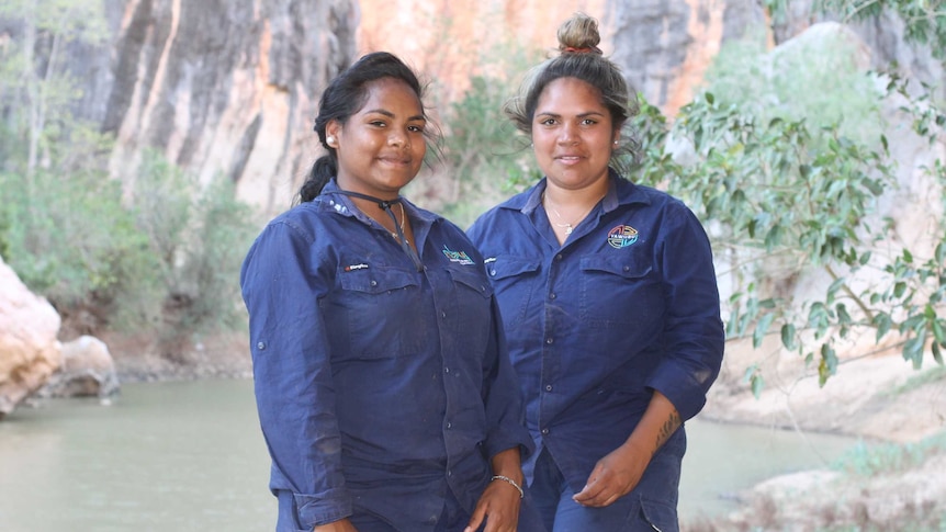Two women indigenous rangers in uniform standing in front of gorge