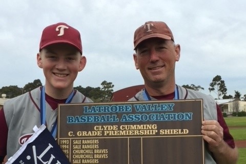 father and son holding plaque