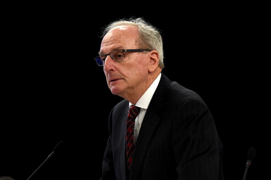 Tim Tobin wearing a suit and in glasses during a hearing.