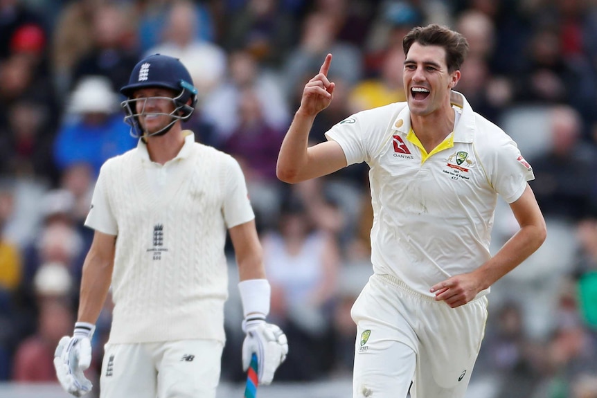 Pat Cummins raises one finger and smiles as Denly grimaces in the background.