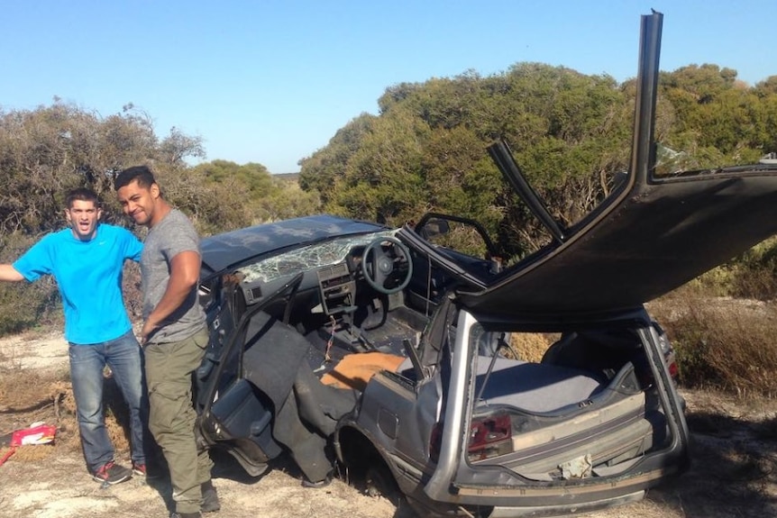 Two men next to a wrecked car