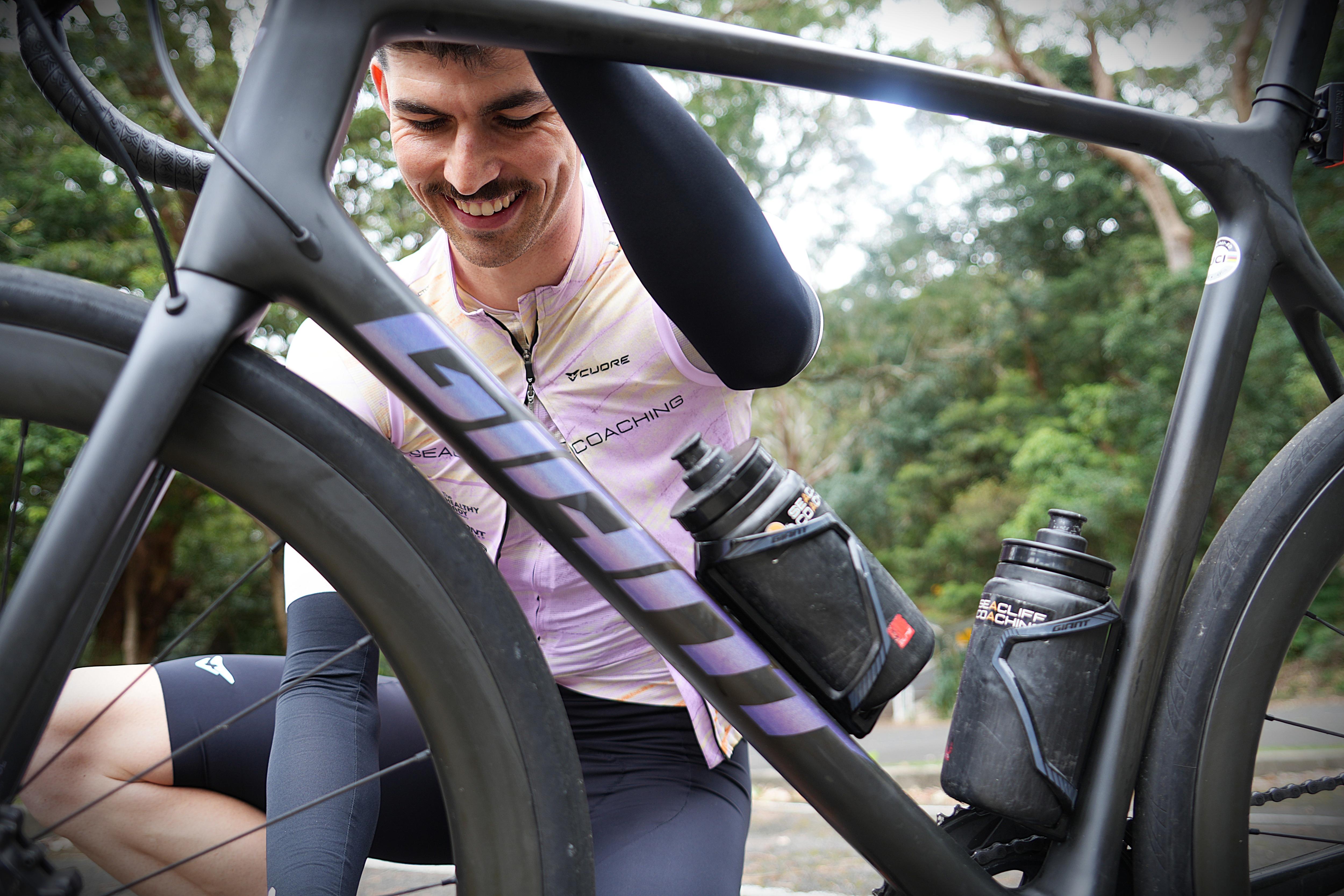 A young man with a moustache tending to his road bicycle. 