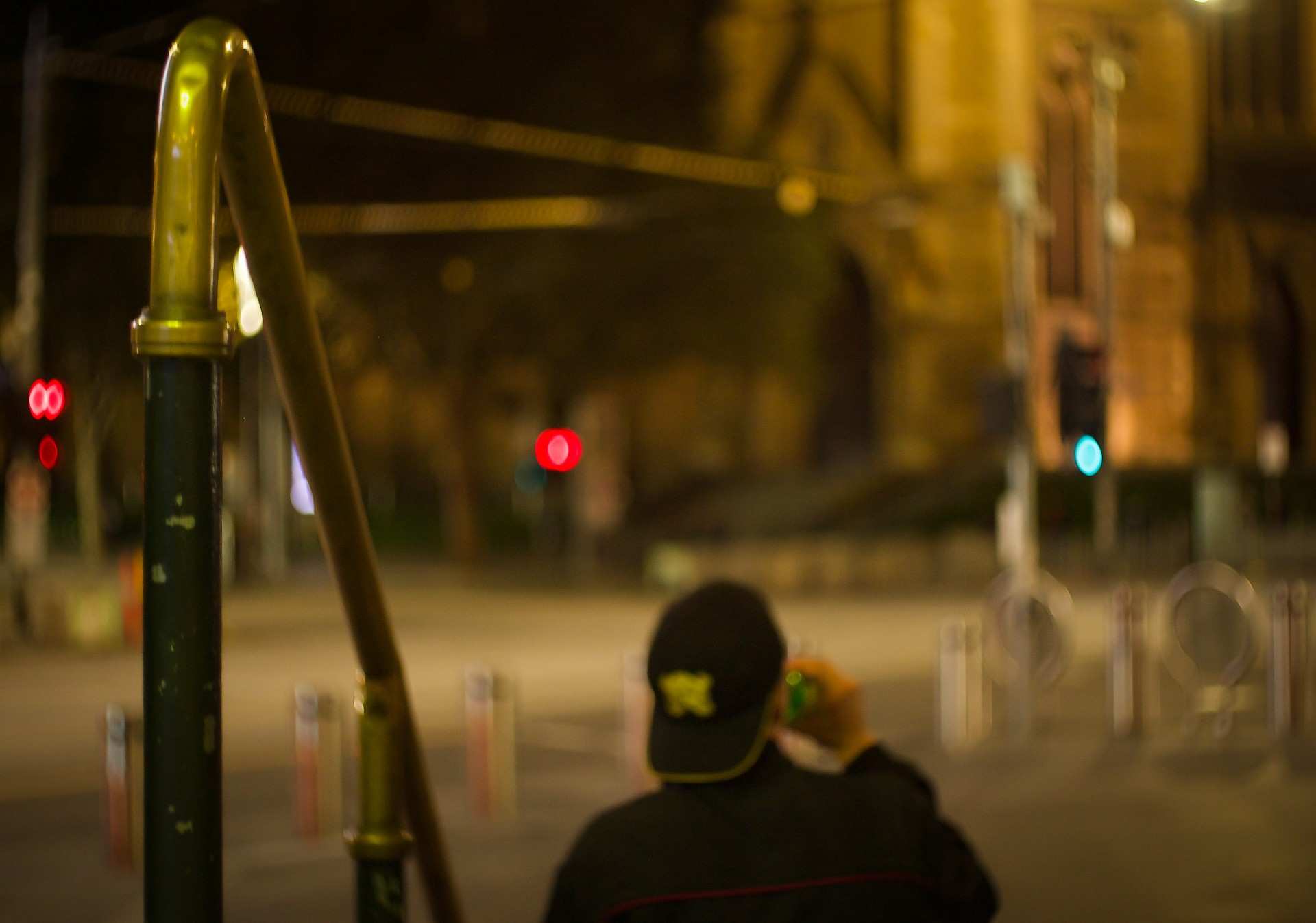 A person can be seen sitting on the steps of Flinders Street Station at night, with St Paul's Cathedral in the background.