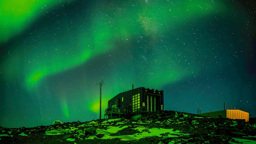 The green lights of aurora australis over a building in Antarctica.
