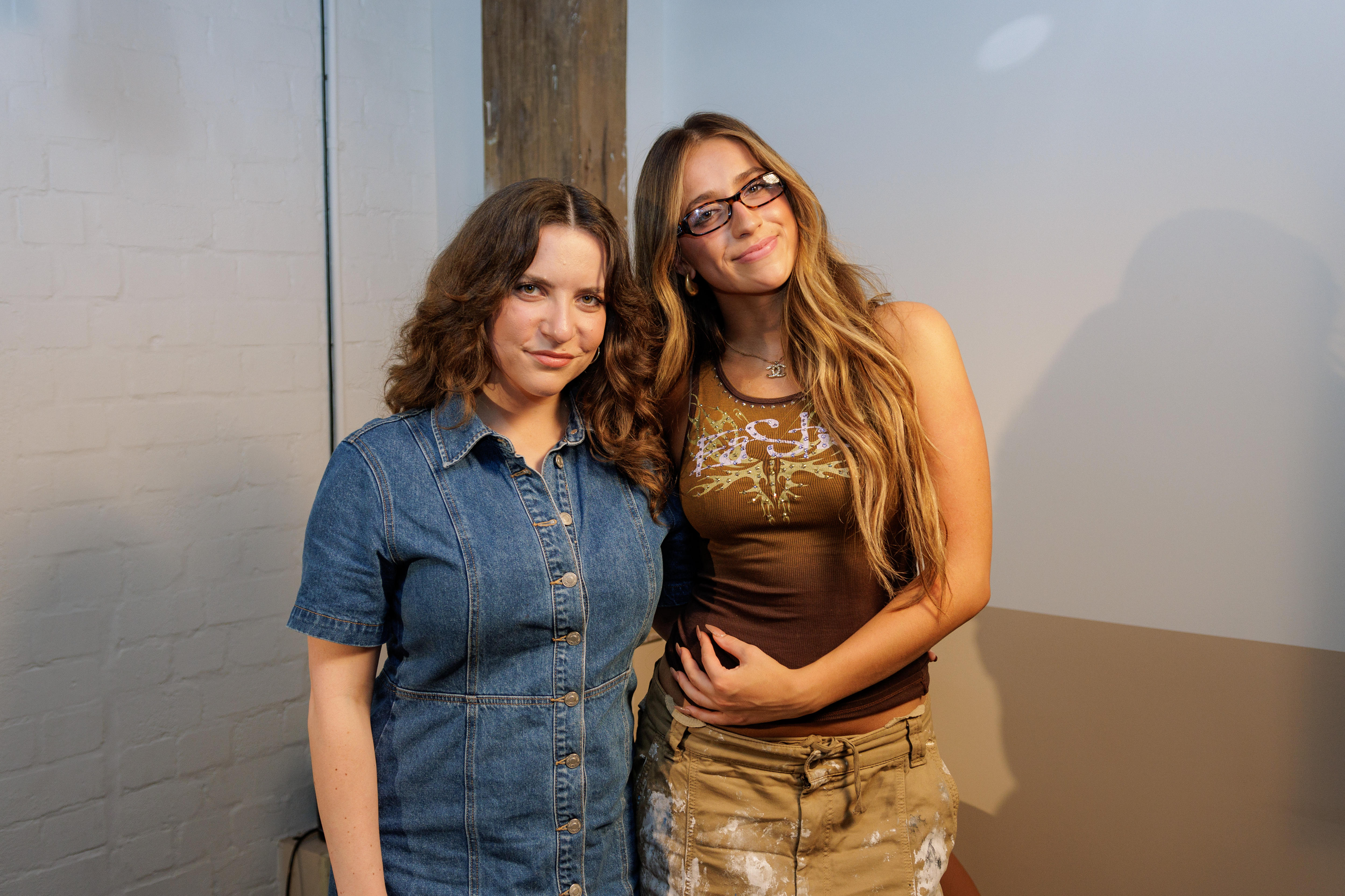 Lucy Smith in as denim dress and Tate McRae in a brown singlet and pants pose together