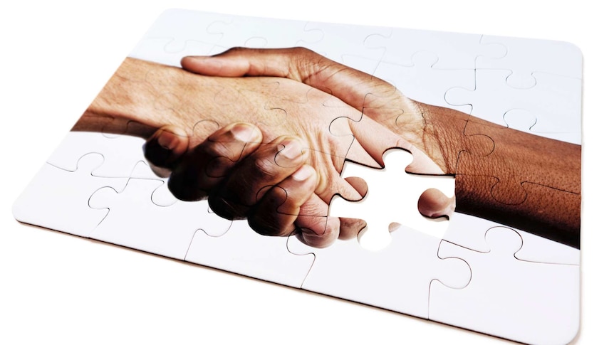 Jigsaw puzzle design of interracial handshake with one piece missing