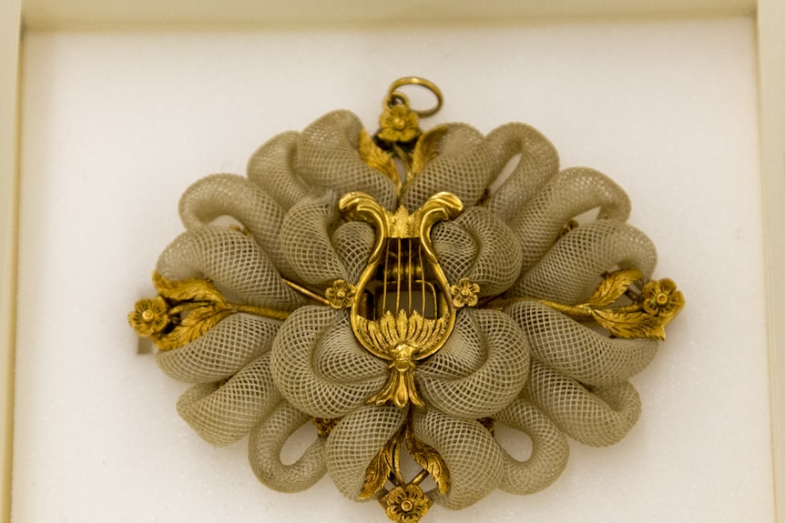 A gold brooch decorated with finely woven tubes.