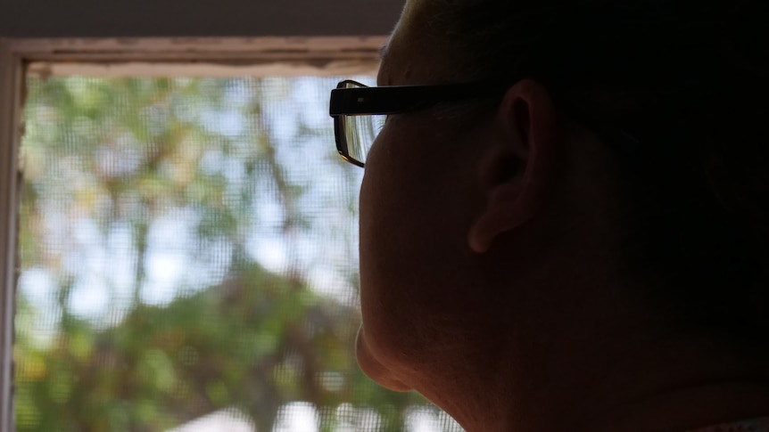 An anonymised woman looking out a window