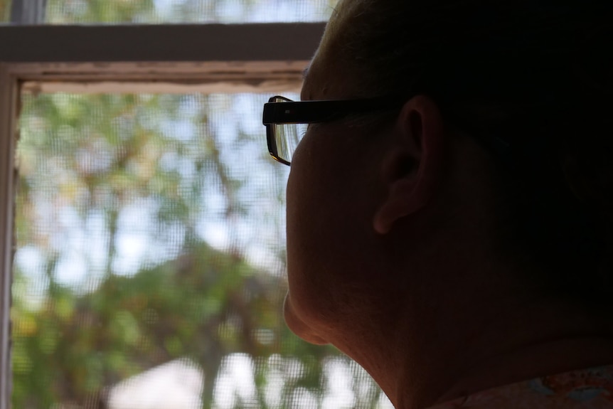 An anonymised woman looking out a window