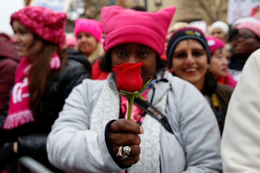 A woman holds a red rose during the Women's March in Washington DC.
