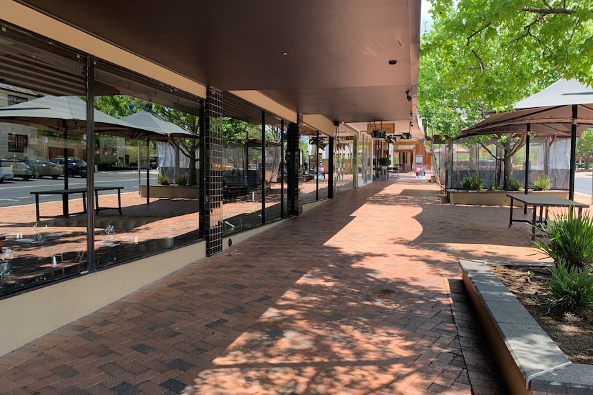 An empty street with shopfronts and outdoor umbrellas 