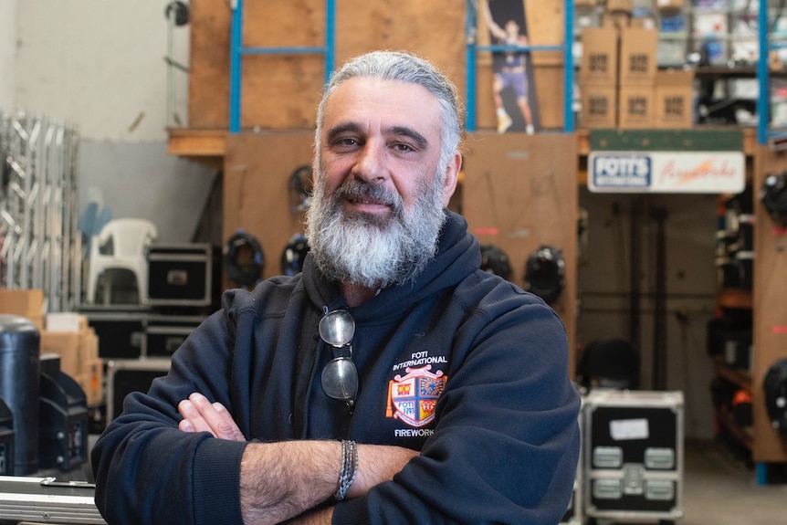 Fortunato stands in a warehouse with his arms crossed.