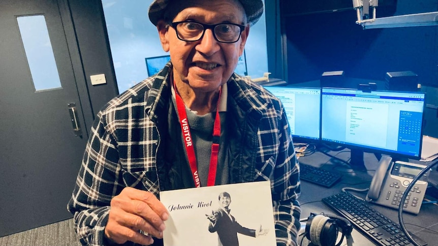 Johnny Nicol in the studio holding a photo of his younger self.