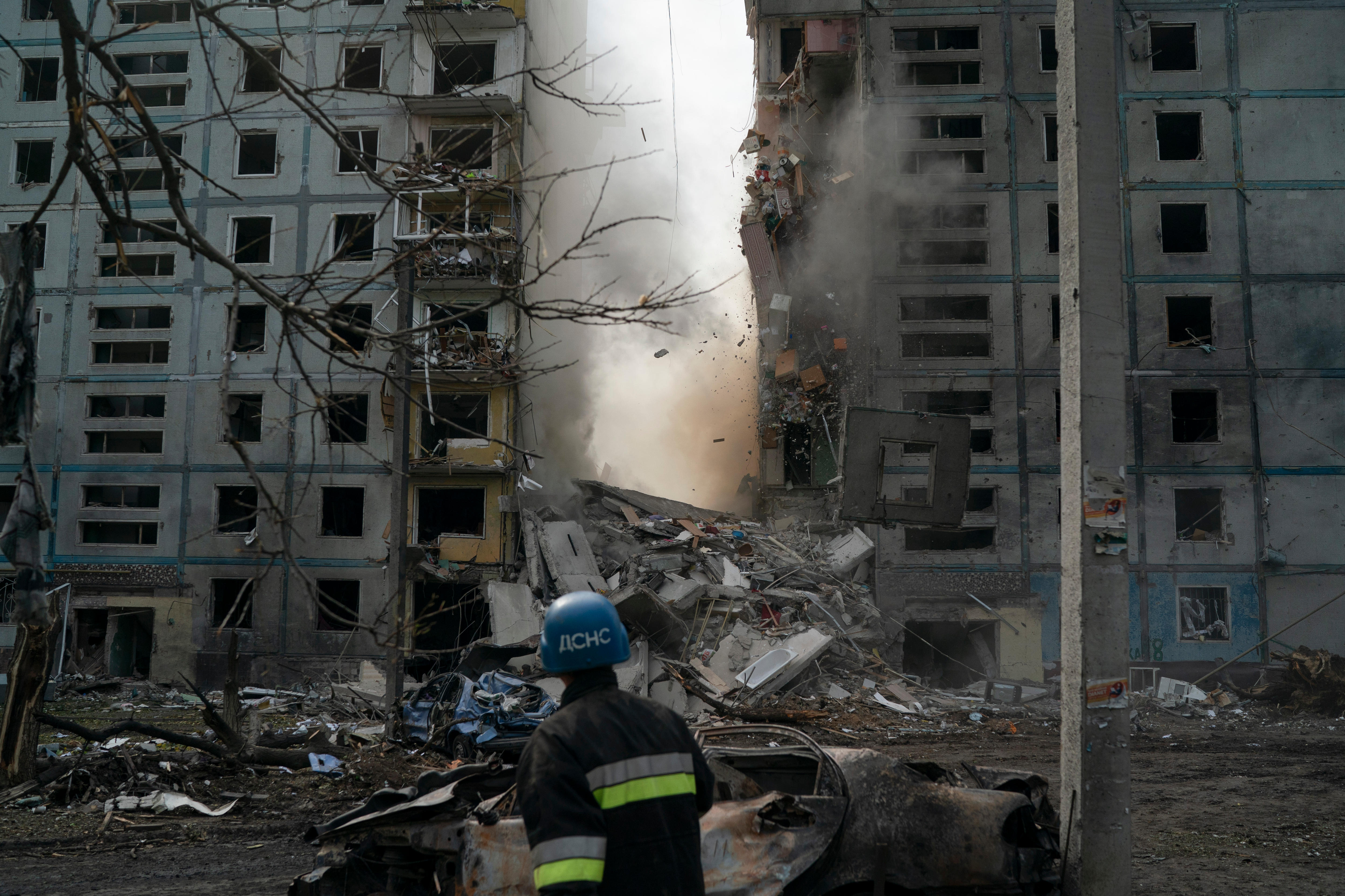 A firefighter looks at a part of a wall falling from a residential building
