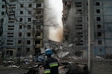 A firefighter looks at a part of a wall falling from a residential building