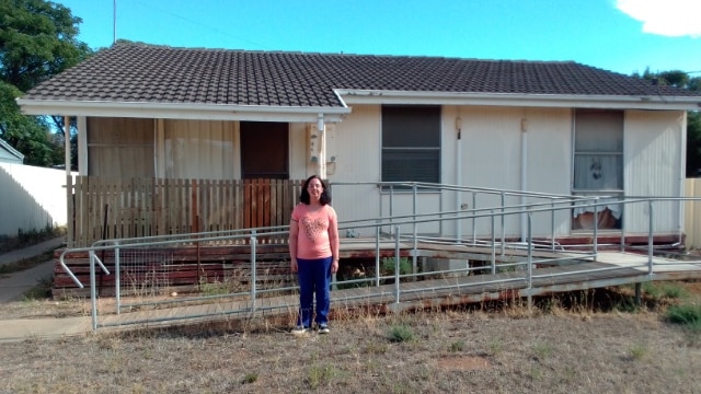 A woman standing in front of a house.