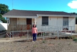 A woman standing in front of a house.