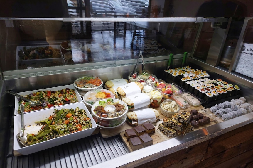 sushi and other food on display in cafe's display cabinet