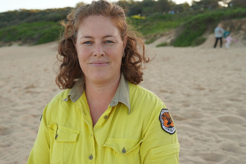A woman in national parks ranger clothes at a beach