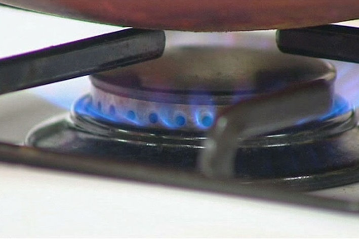 A blue flame emitting from a gas burner on a stove top