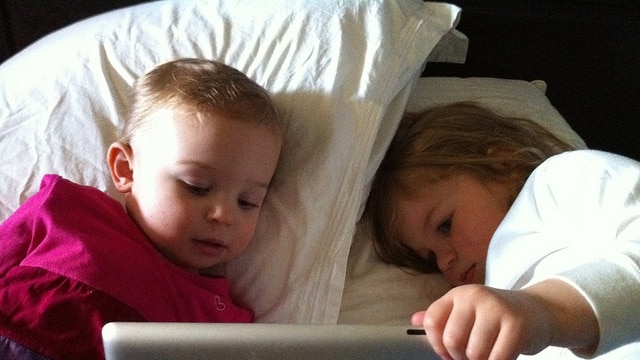 Children use a tablet in bed