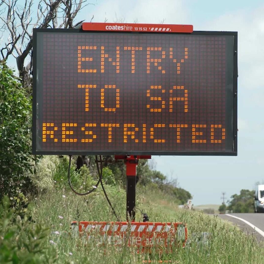 An electronic sign saying "entry to SA restricted" as a truck goes past in the opposite direction