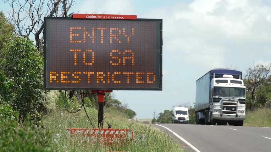 An electronic sign saying "entry to SA restricted" as a truck goes past in the opposite direction