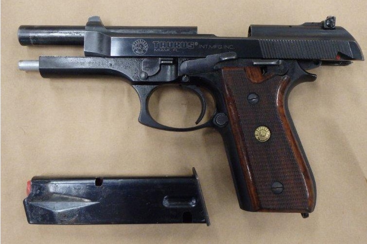 A close-up image of a handgun with the clip removed and lying below the gun.