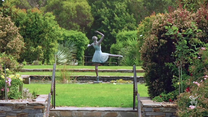 Large formal garden with a statue of a girl doing ballet in the background