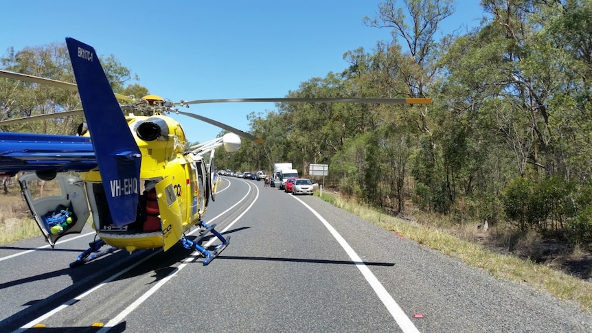 Rescue helicopter parked on the Bruce Highway near Gin Gin, with a long line of banked up traffic disappearing into the distance