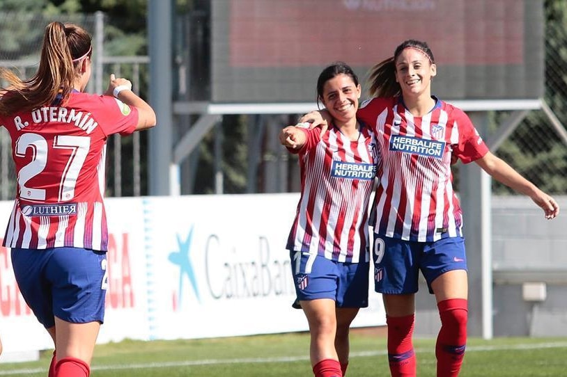 Alex Chidiac embraces one Atletico Madrid teammate, while pointing at another.