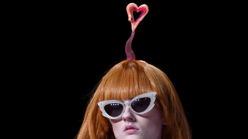 A heart-shaped symbol is attached to the head of a model as she walks down the catwalk.