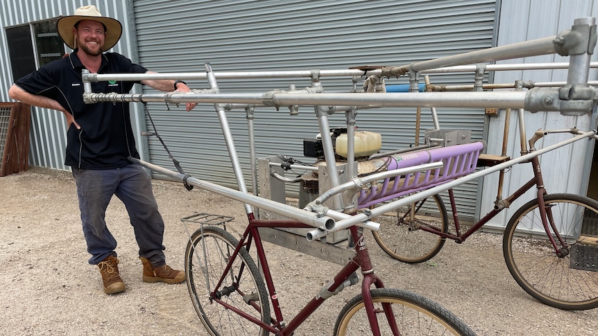 Image of a man standing next to a bike with metal bars around it. 