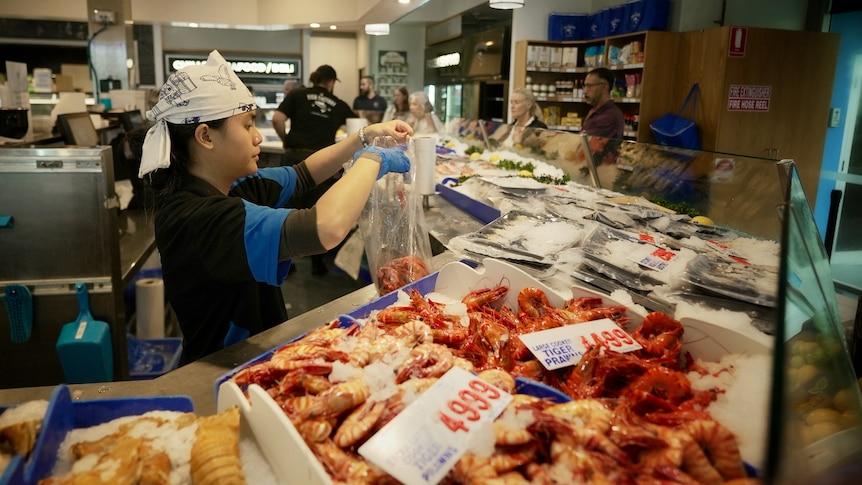 Staff serving customers at a fish market.