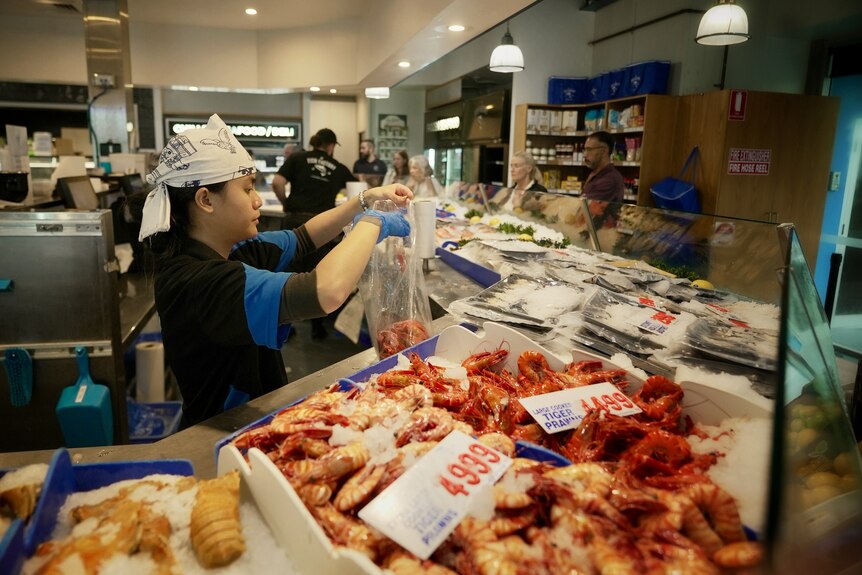 Staff serving customers at a fish market.