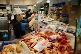 Staff serving customers at a fish market.