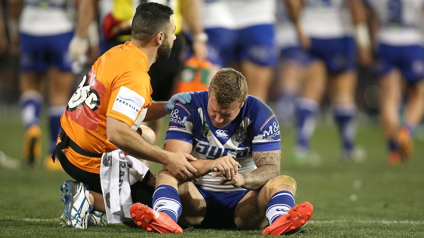 Trent Hodkinson is treated on the field for his injured wrist