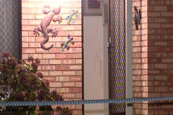 A close up of the flywire and front door to a brick house in Armadale, with marks on the wall and police tape in the foreground.