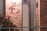 A close up of the flywire and front door to a brick house in Armadale, with marks on the wall and police tape in the foreground.