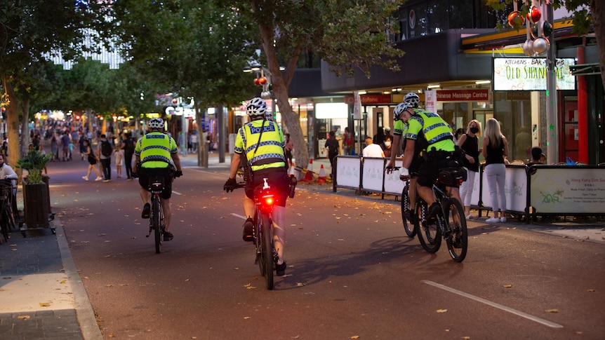 A group of four police officers in high-visibility vests on patrol in Northbridge.
