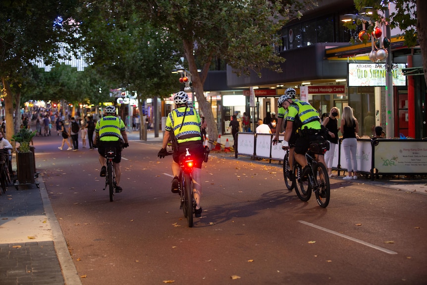 A group of four police officers in high-visibility vests on patrol in Northbridge.