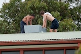 Six youths are seen protesting on the roof of the Melbourne Youth Justice Centre