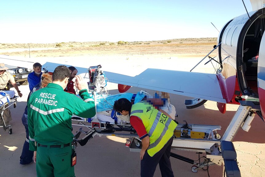 Medical staff load a patient onto a Royal Flying Doctor Service plane.